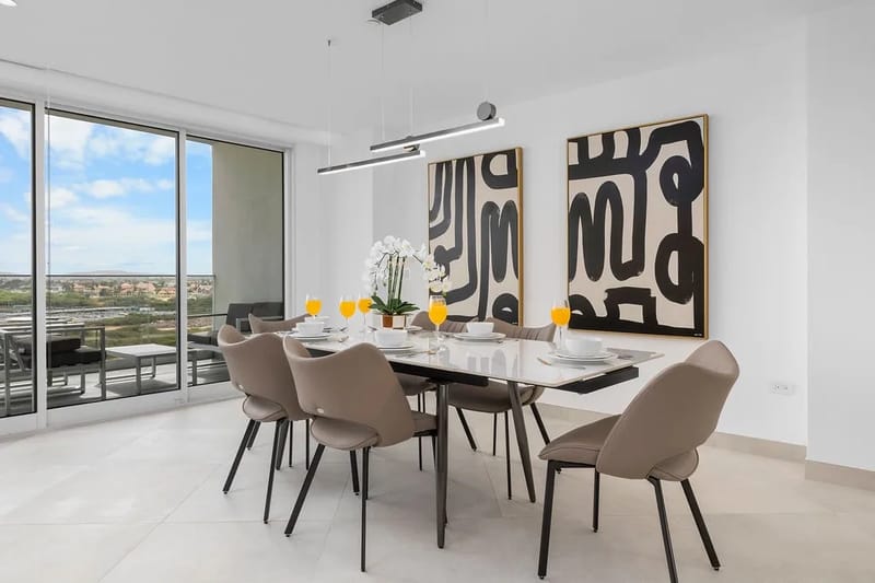 Reúnanse alrededor de esta elegante mesa de comedor, donde el arte moderno se combina con vistas luminosas. Tus mañanas comienzan con jugo fresco y luz del sol que entra por las ventanas de piso a techo.