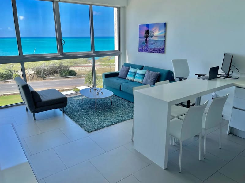Espacio de estar luminoso y abierto con ventanas de piso a techo y vistas al mar.