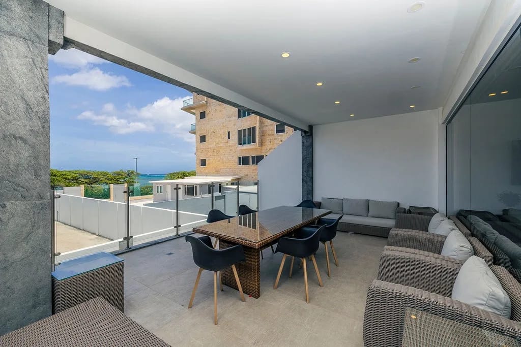 Relax in your covered terrace with ocean glimpses, where comfortable seating and dining await. The perfect spot to unwind morning to evening, blending indoor comfort with coastal breezes.