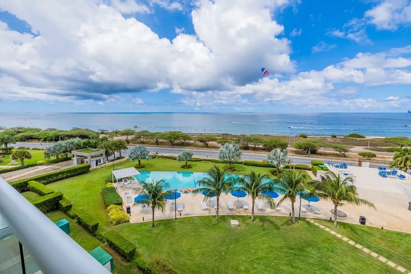 Vista aérea de la propiedad frente a la playa, los jardines, la piscina, la carretera costera y la costa.