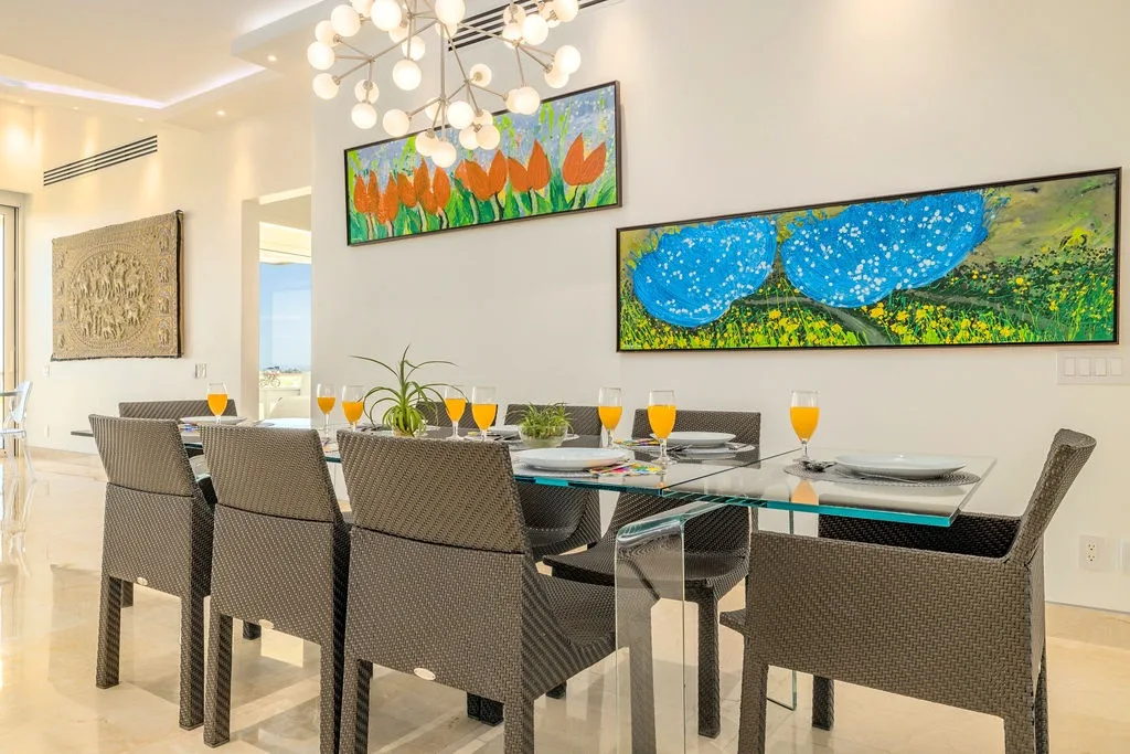 Reúnanse alrededor de esta elegante mesa de comedor, donde las coloridas obras de arte y la iluminación moderna crean el entorno perfecto para disfrutar juntos de comidas memorables.