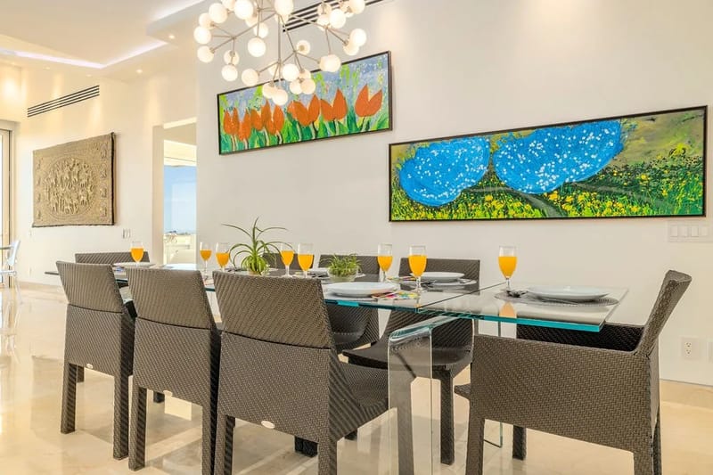 Gather around this elegant dining table where vibrant artwork and modern lighting create the perfect backdrop for your memorable meals together.
