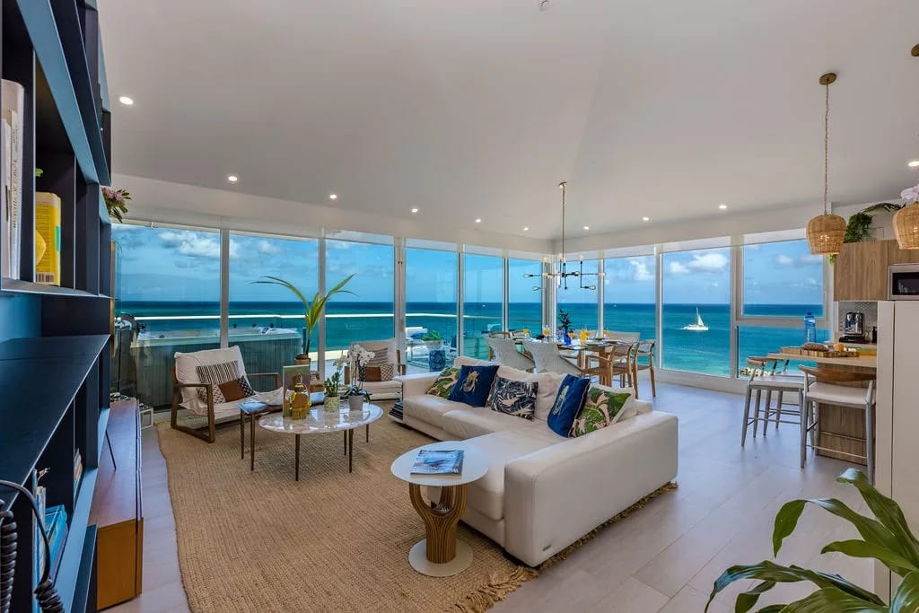 Relax in this bright, open living space where floor-to-ceiling windows frame stunning ocean views. Cozy seating, coastal decor, and a seamless flow into the dining and kitchen areas make your stay effortless.