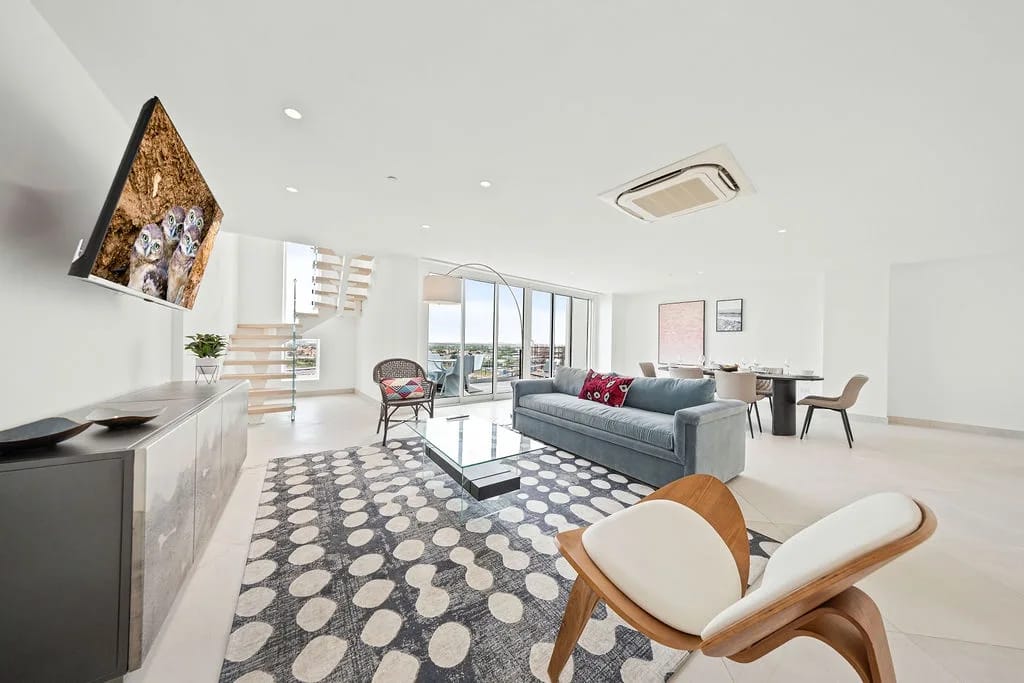 Espacio de estar abierto con muebles modernos, arte elegante y amplias vistas de la ciudad.