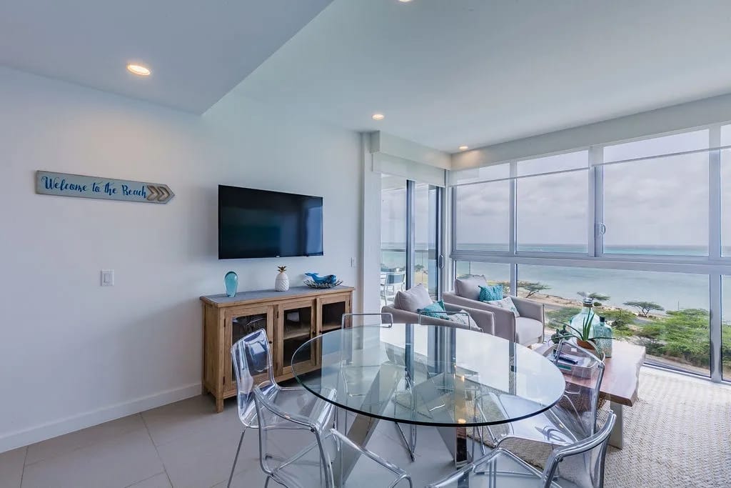 Sala de estar y comedor de concepto abierto con acceso a un balcón privado con vistas al mar.