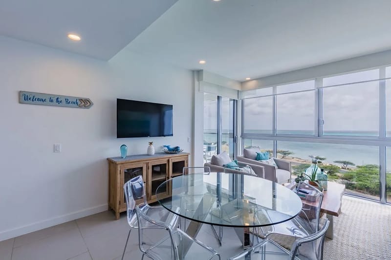 Sala de estar y comedor de concepto abierto con acceso a un balcón privado con vistas al mar.