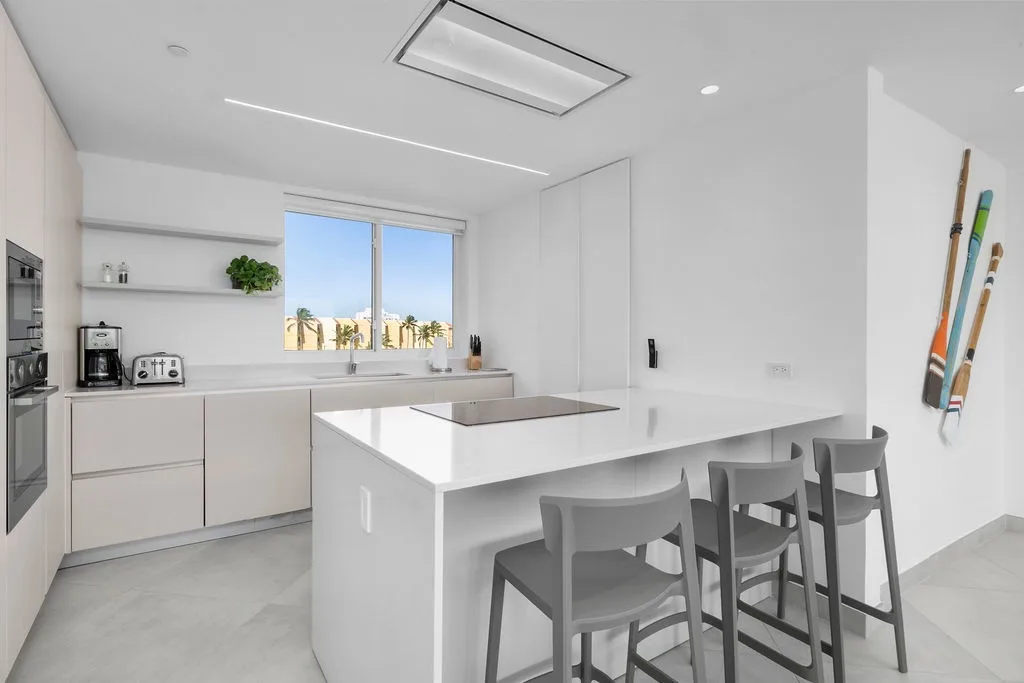 Cocina moderna con electrodomésticos de acero inoxidable, una isla con asientos de barra y luz natural.