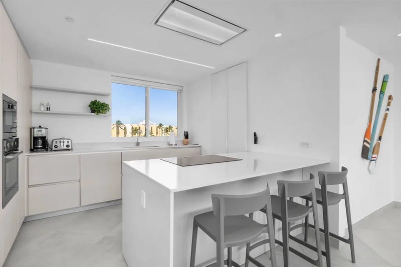 Cocina moderna con electrodomésticos de acero inoxidable, una isla con asientos de barra y luz natural.