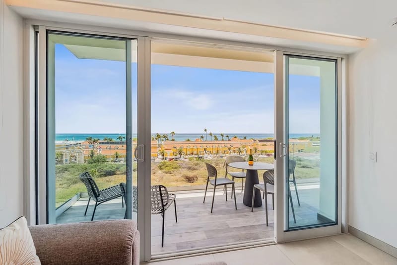 Sal por las puertas corredizas a tu balcón privado, donde las vistas al mar y la brisa costera acompañan tu café de la mañana o tu copa de vino al atardecer en tu propia mesa de comedor al aire libre.