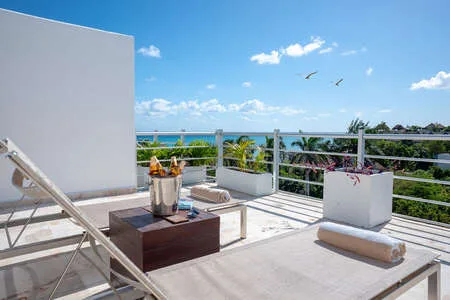 Una terraza soleada en la azotea con asientos y vistas al mar.