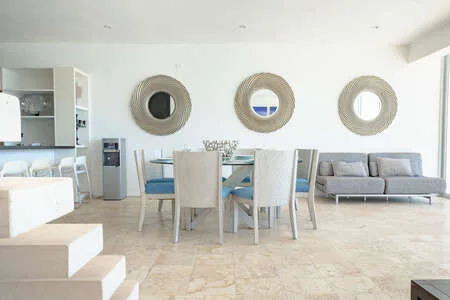 Una luminosa sala de estar y comedor diáfana con mesa, asientos y espejos redondos en la pared.