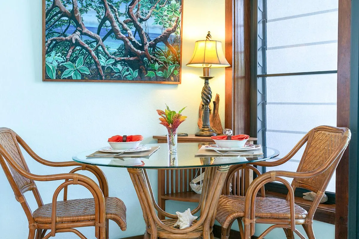 Un comedor interior con una mesa de vidrio y asientos tejidos.