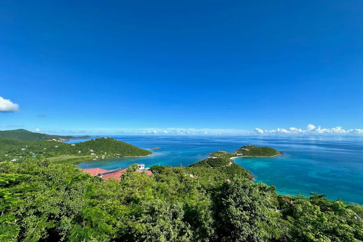 A wide coastal view shows green hills, blue water, and small islands.