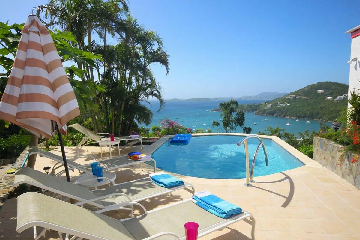 A swimming pool and sun loungers overlook the sea.