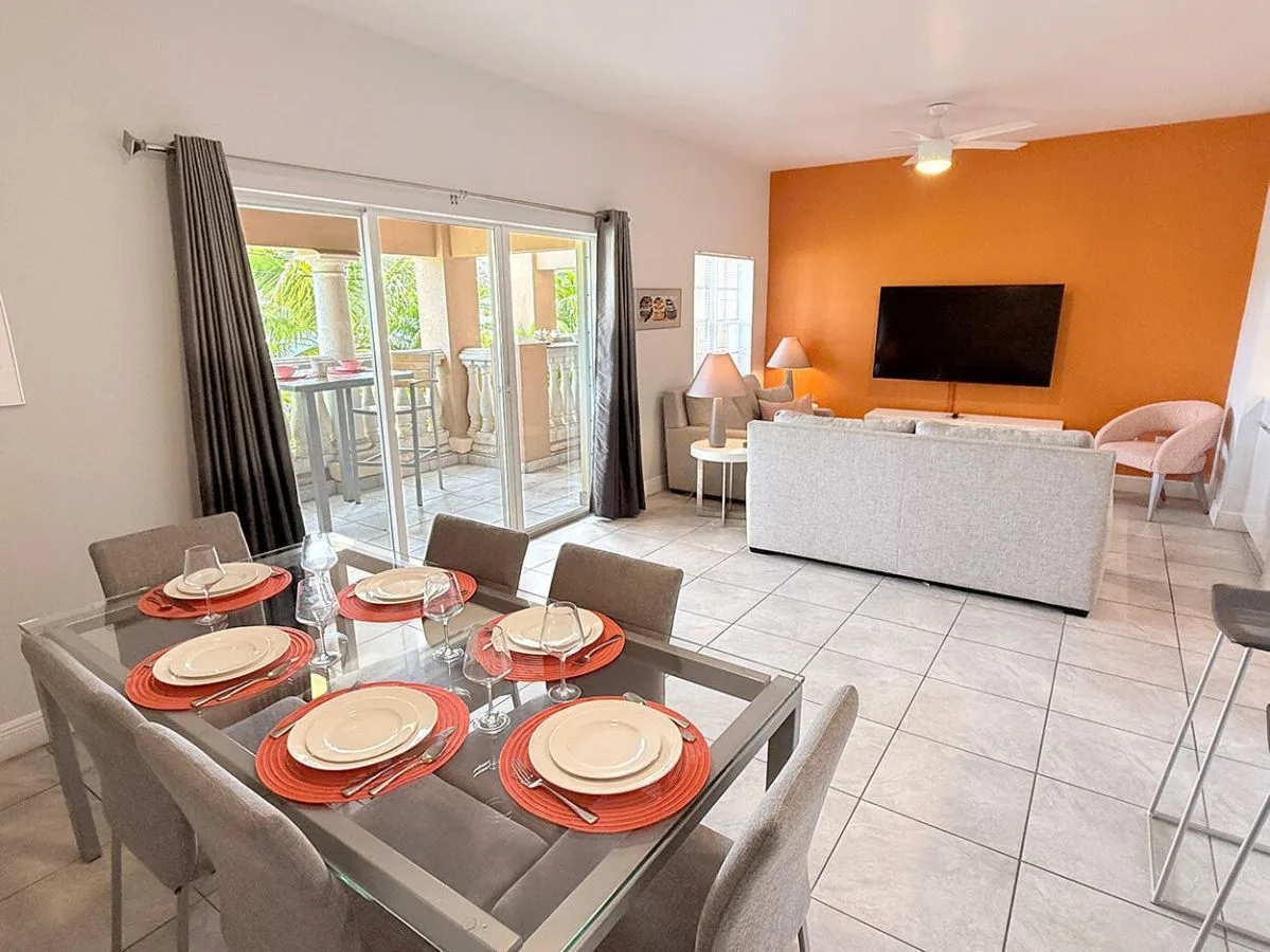 Una sala de estar y comedor con una mesa frente a un sofá y un televisor.