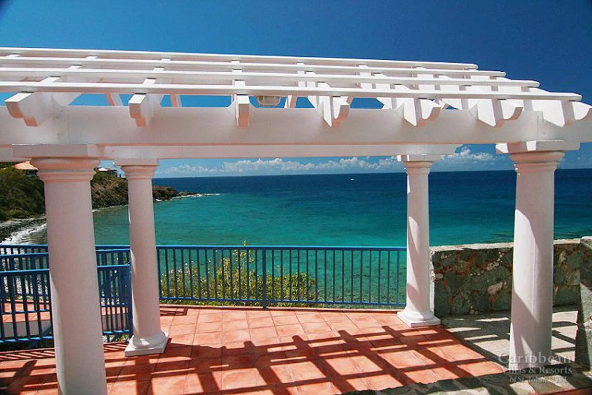 Un patio junto al mar con una pérgola blanca frente al océano.