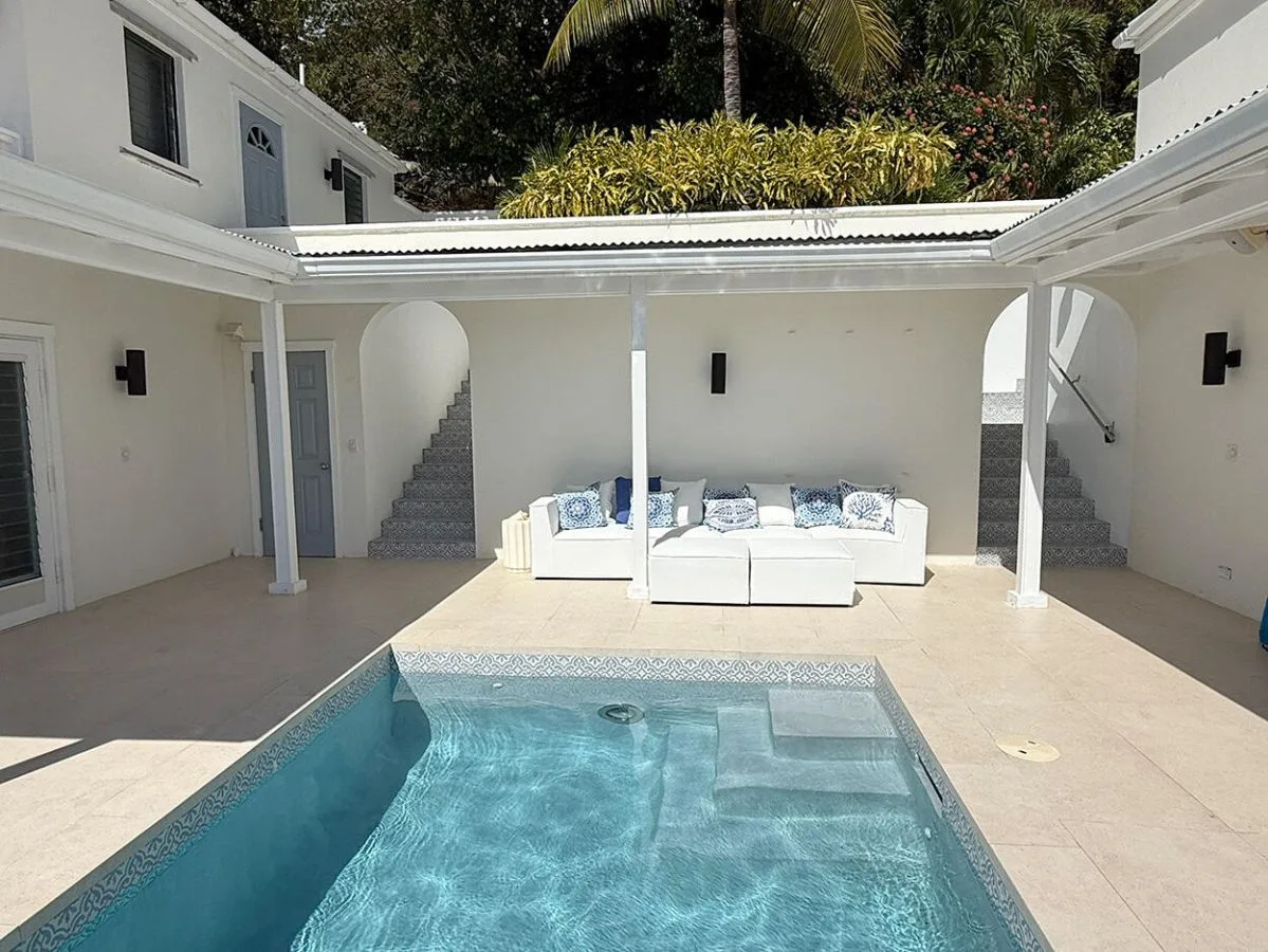 Una piscina y una zona de asientos están en un patio luminoso.