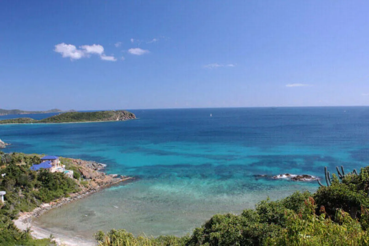 A coastal bay with turquoise water, rocky shoreline, and distant islands.