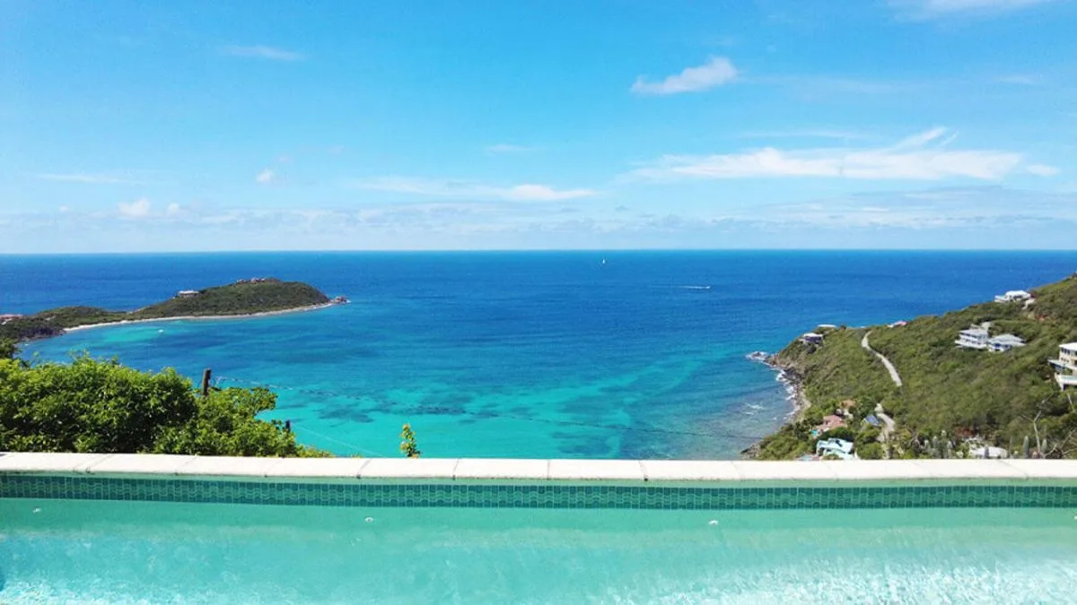 Vista del océano desde una piscina infinita, con una pequeña isla mar adentro.