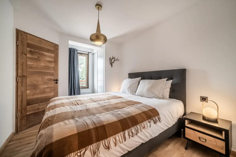 Dormitorio moderno con una cama grande, ropa de cama blanca, cabecero gris y lámparas de mesilla.