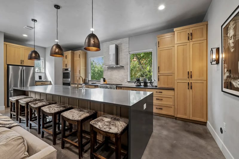 Modern kitchen with wooden cabinets, stainless-steel appliances, a large island, and bar stools.
