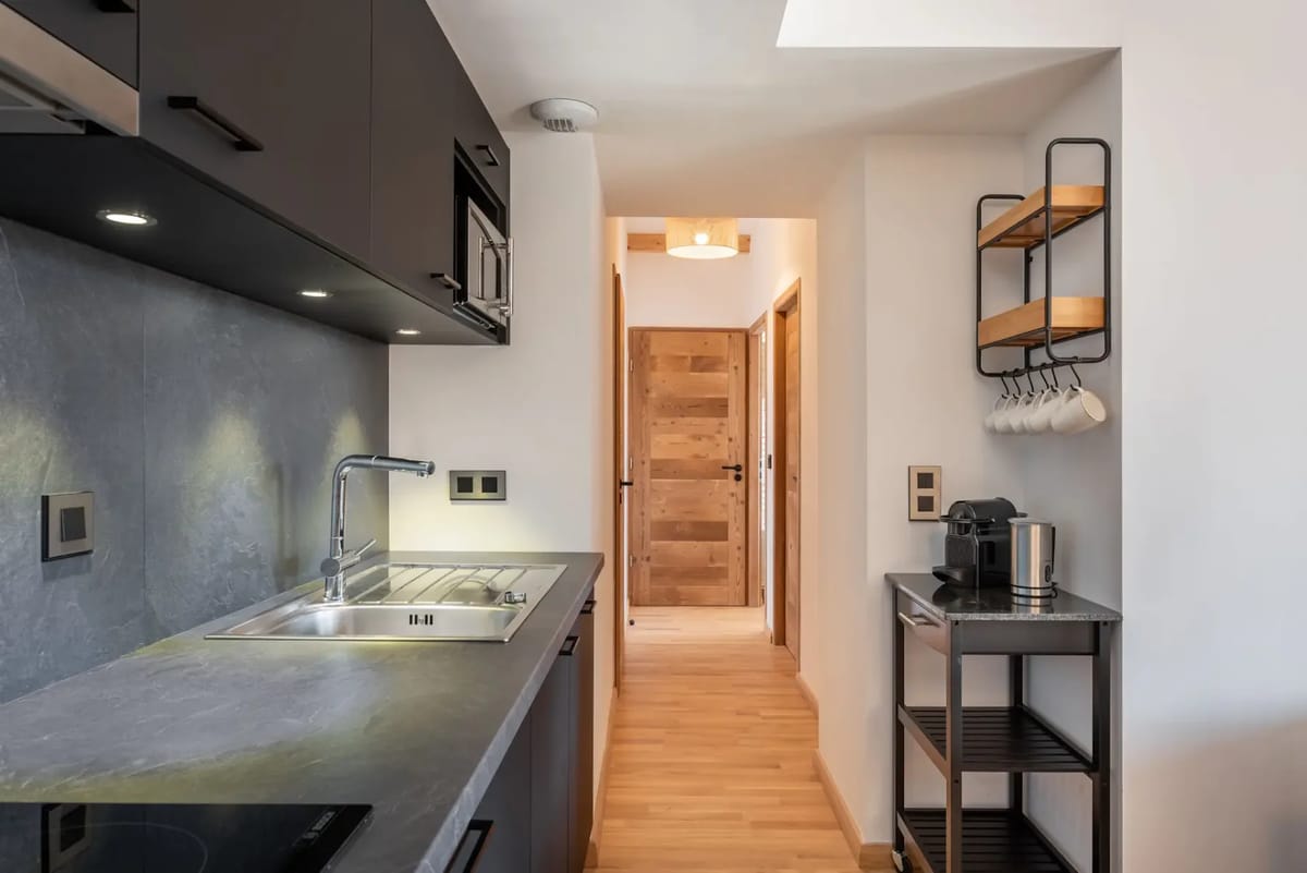 Cocina moderna con armarios oscuros, encimeras elegantes y suelo revestido de madera.