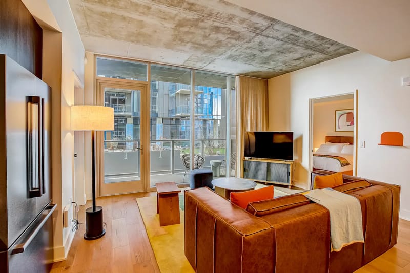 Sala de estar moderna con sofá, cojines coloridos, televisor y mesa de centro de madera.