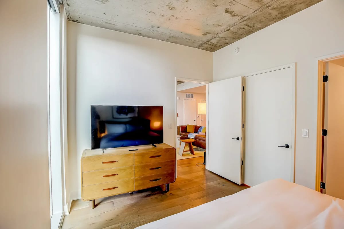Dormitorio con cómoda de madera, televisor de pantalla plana y decoración minimalista.