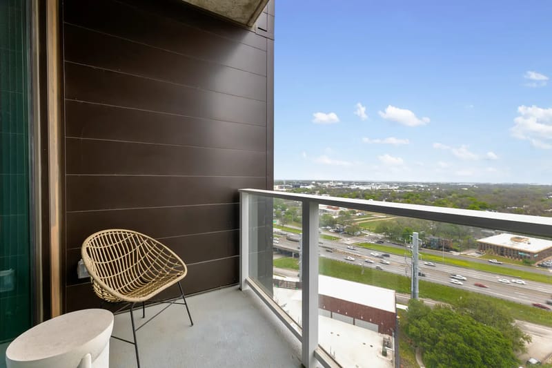 Balcón con una silla de mimbre y una mesa pequeña con vistas al paisaje circundante.