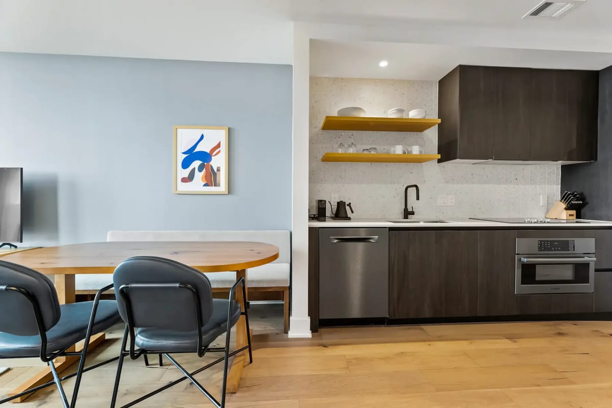 Modern kitchen and dining area with dark cabinets, stainless steel appliances, and a light countertop.