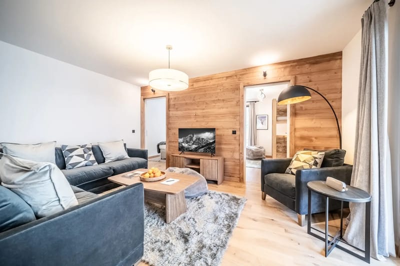 Salón moderno con dos sofás, una mesa de centro de madera y un televisor.