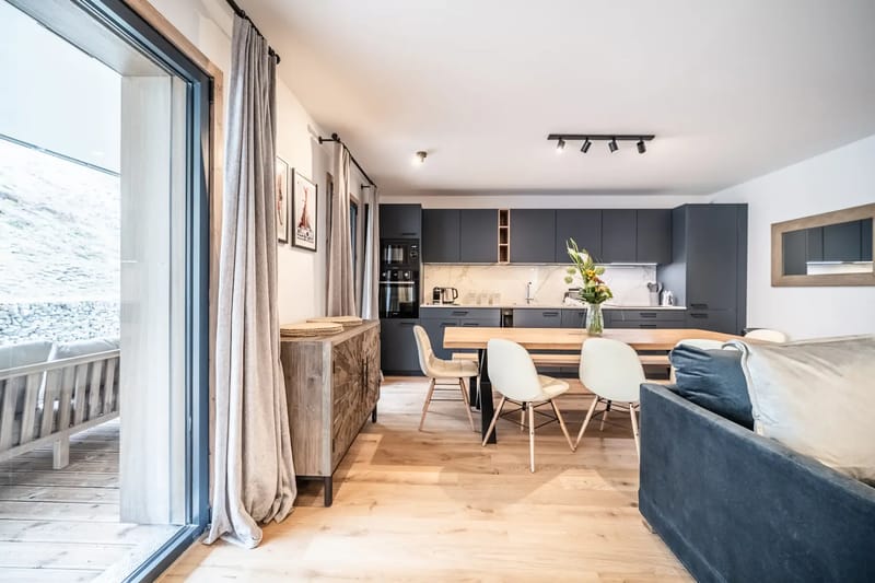 Cocina moderna con muebles grises y una mesa de comedor de madera con seis sillas.