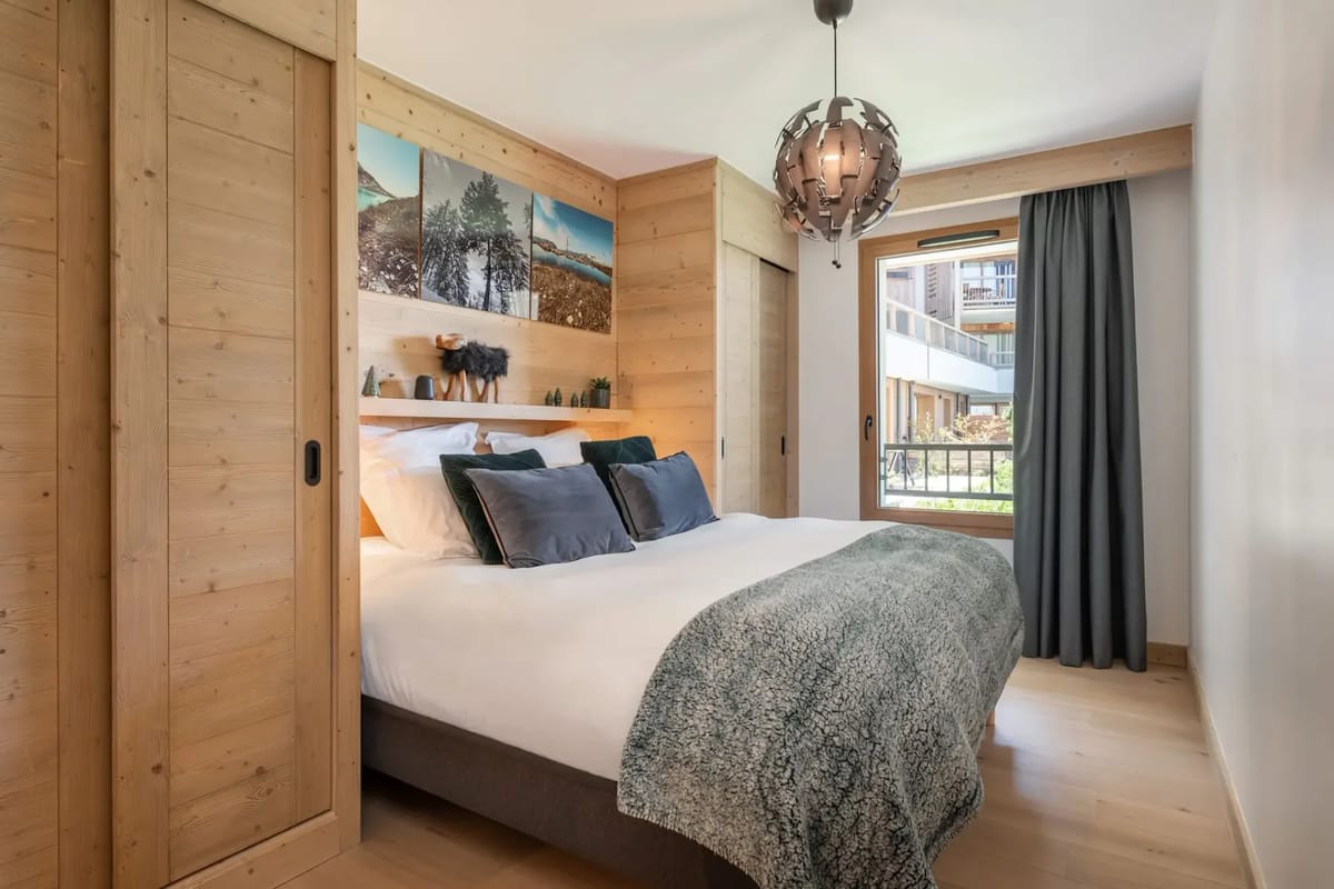Dormitorio acogedor con detalles de madera, una cama de matrimonio, una obra de arte con un paisaje y una ventana grande.