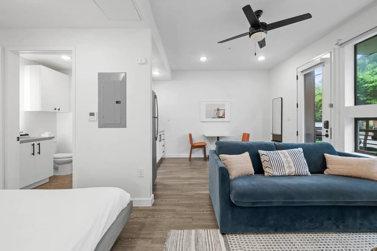 Sala de estar moderna con un sofá azul, una cama y un comedor.