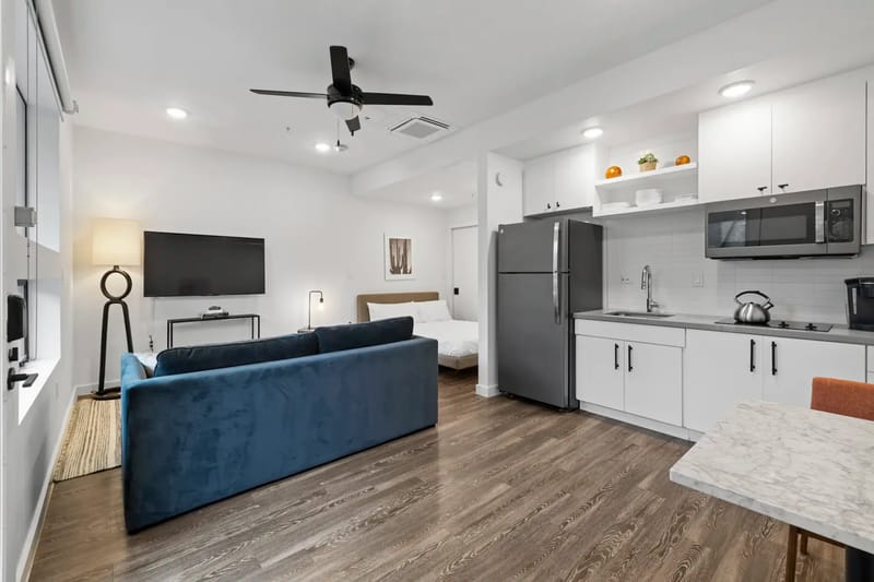 Apartamento tipo estudio con una cocina pequeña, un comedor, un sofá, un televisor y una cama.
