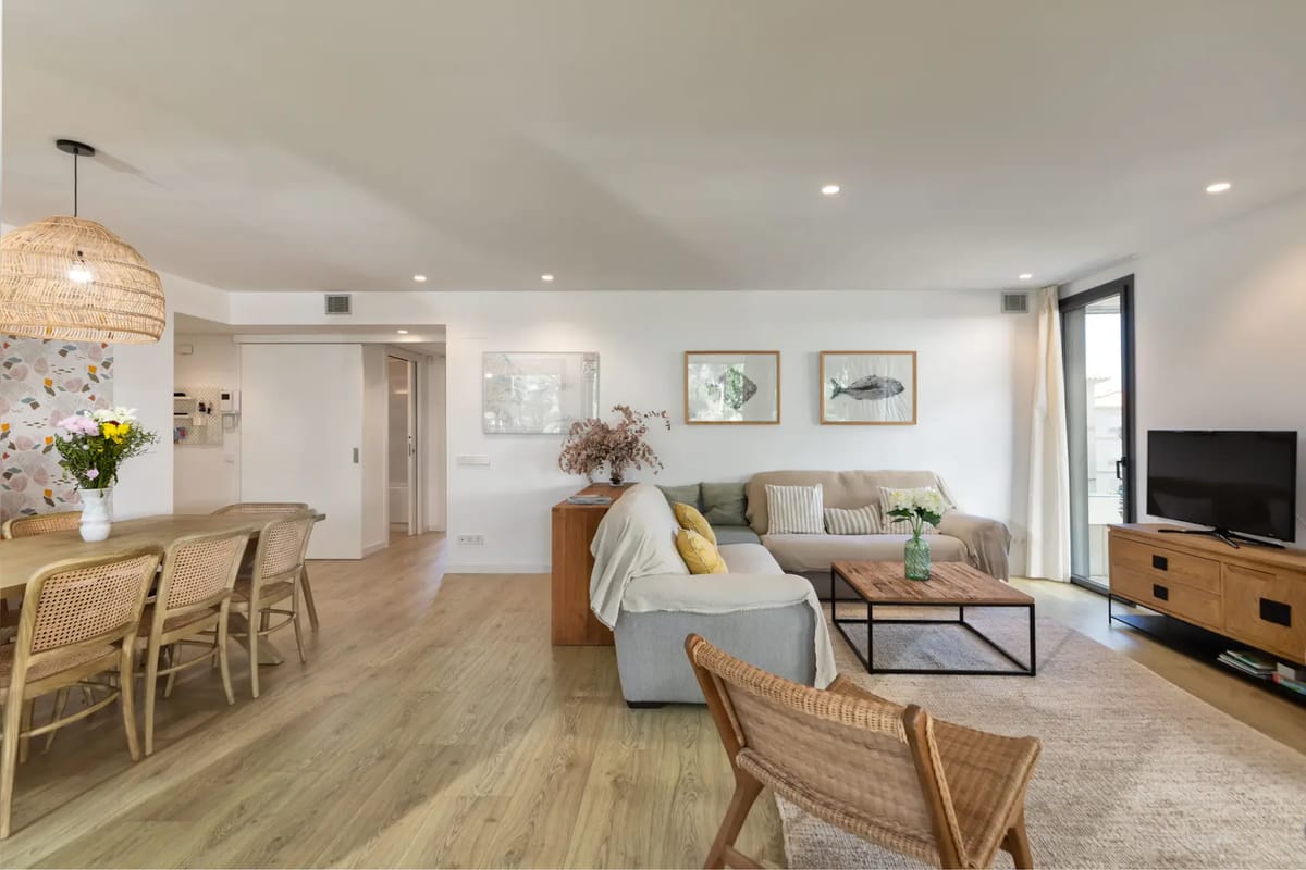 Modern open-plan living area with wooden flooring, a cozy seating area, and a kitchen.