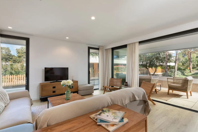 Modern open-plan living area with wooden flooring, a cozy seating area, and a kitchen with pendant lights.