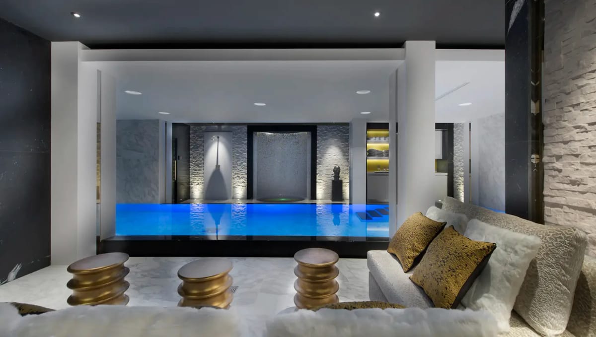 Indoor pool area with blue lighting, modern decor, sofas, and accent tables.