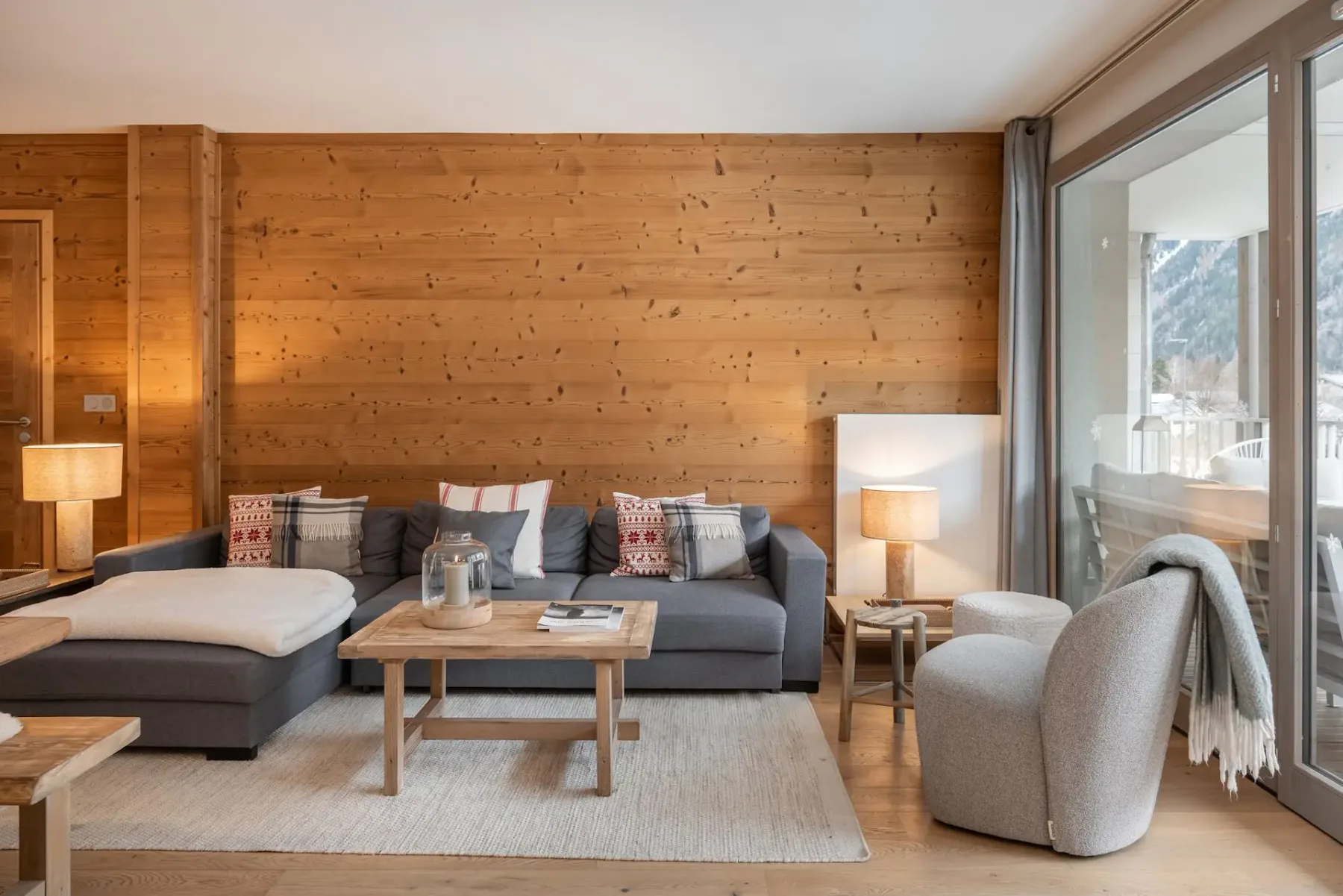 Un salón con asientos y una mesa de centro junto a grandes puertas de cristal.