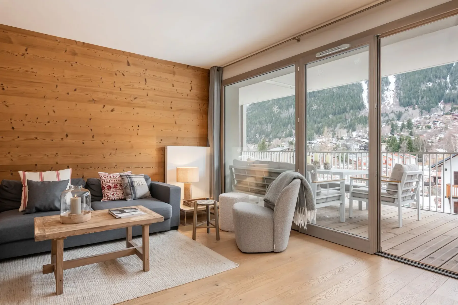 Un salón con asientos, una pared de madera y grandes ventanales que dan a un balcón.