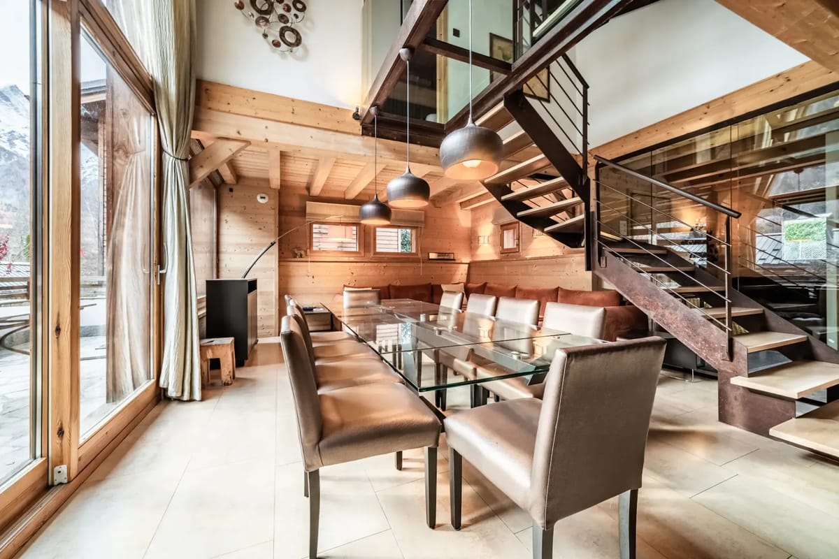 A living room with a wooden staircase and a dining table.