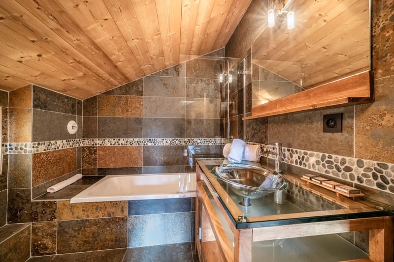 Un baño con suelo de madera y paredes alicatadas.