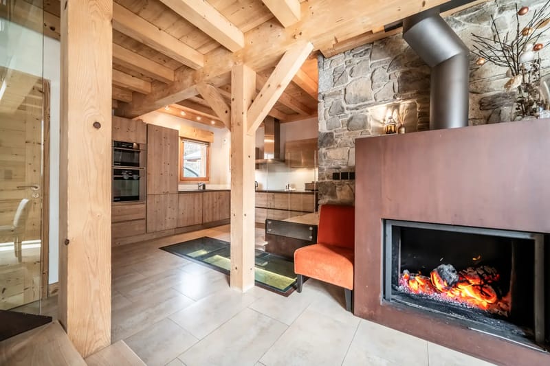 Un salón con una escalera de madera, una mesa de comedor y una chimenea.