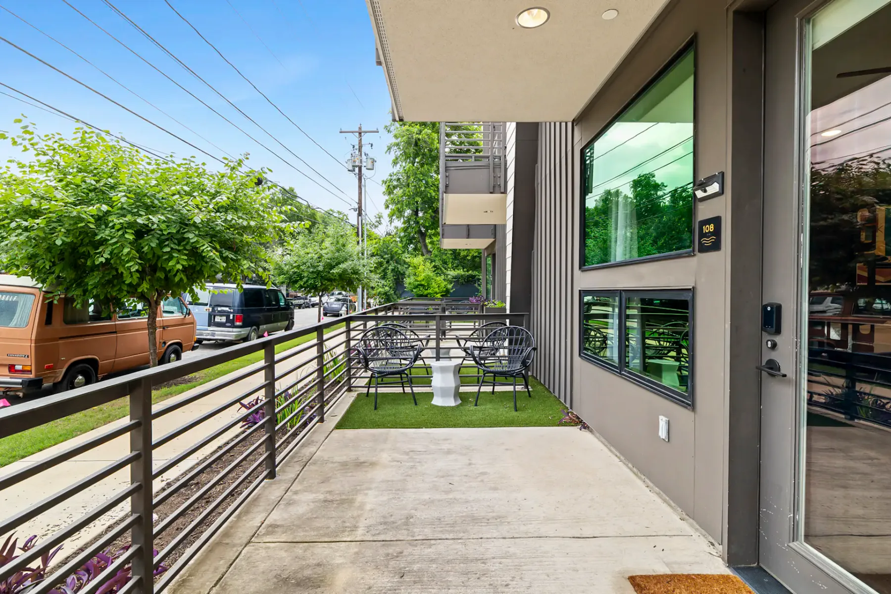 Outdoor patio with metal chairs and a small table on artificial grass beside the building.