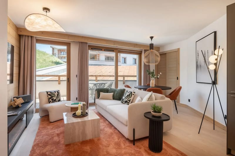 Salón moderno con grandes ventanales, revestimiento de madera clara, sofá blanco, detalles negros, un televisor montado en la pared y una alfombra naranja.