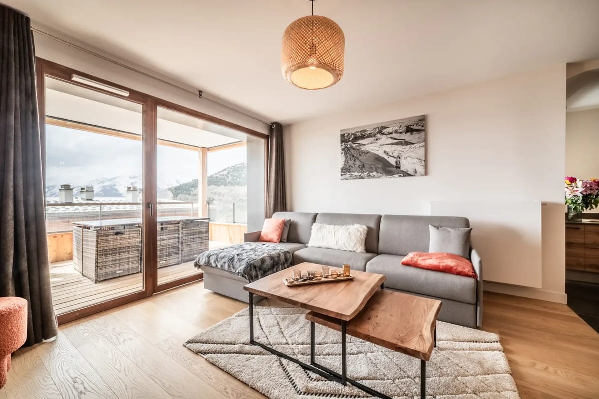 Living room with wooden interiors, seating and mountain views.