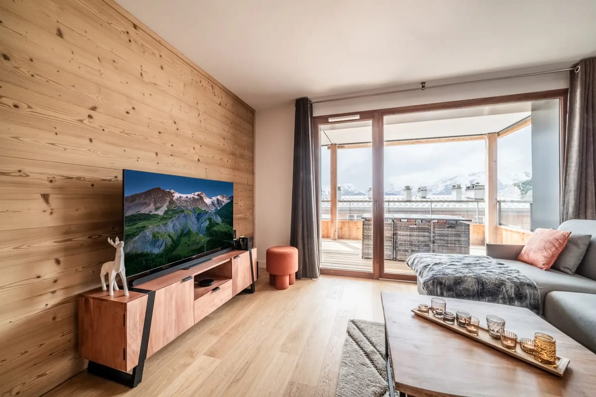 Living room with wooden interiors, seating and mountain views.
