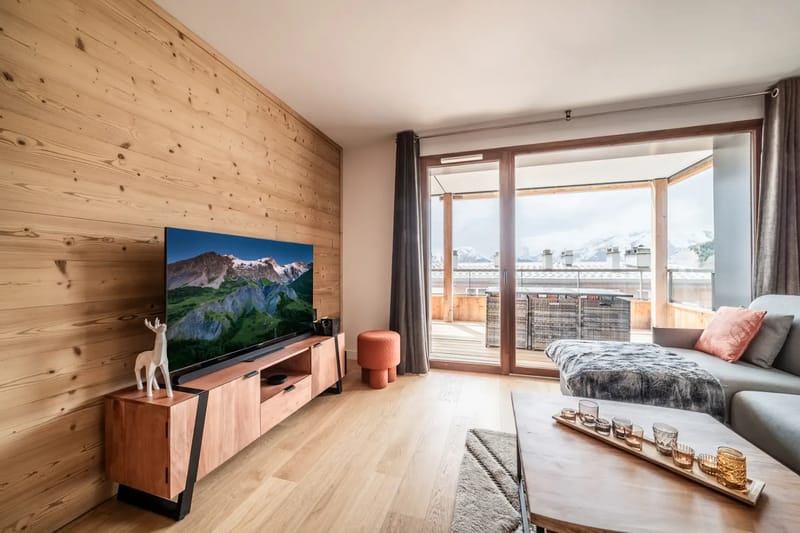 Sala de estar con interiores de madera, asientos y vistas a las montañas.