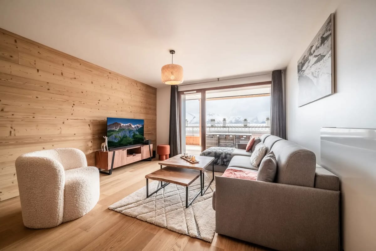 Living room with wooden interiors, seating and mountain views.