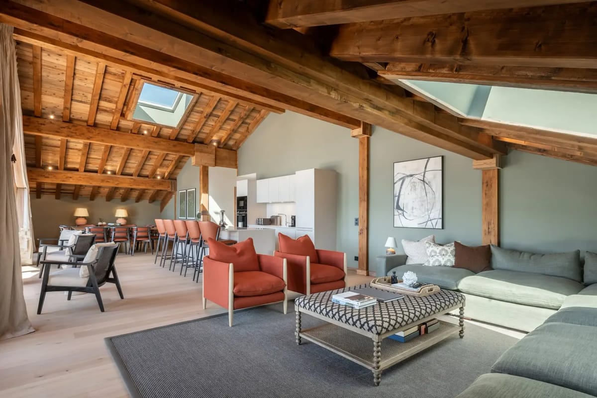 Cozy attic living room with wood beams, large windows, a TV, and mountain views.